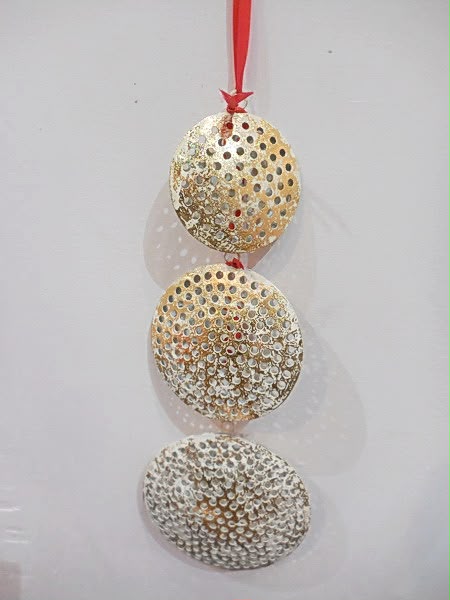 Three pierced metal hanging ornaments on a red ribbon