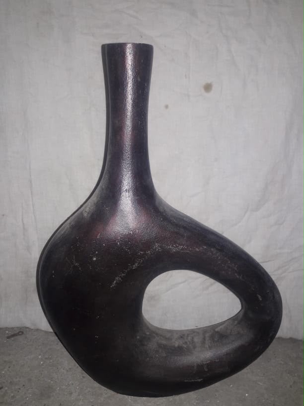 Dark brown sculptural metal vase on a cloth backdrop